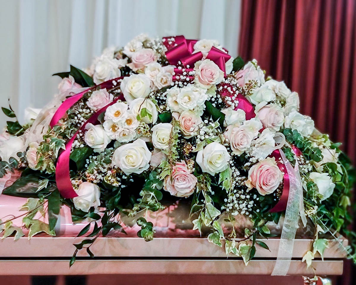 Elegant white and blush roses with garden greenery half casket cover by Annaville Florist